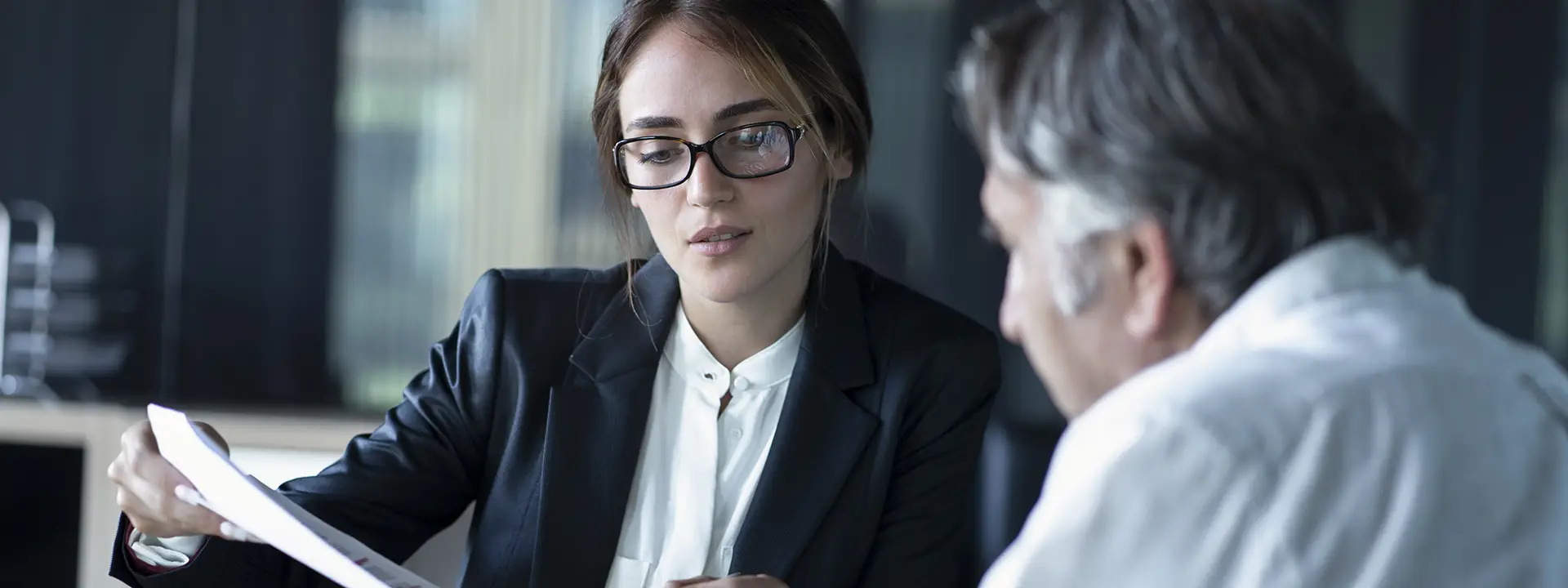 A financial adviser in a serious conversation with a client while reviewing a document