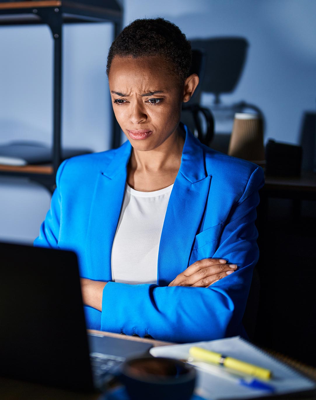 A business woman at her computer with her arms crossed.